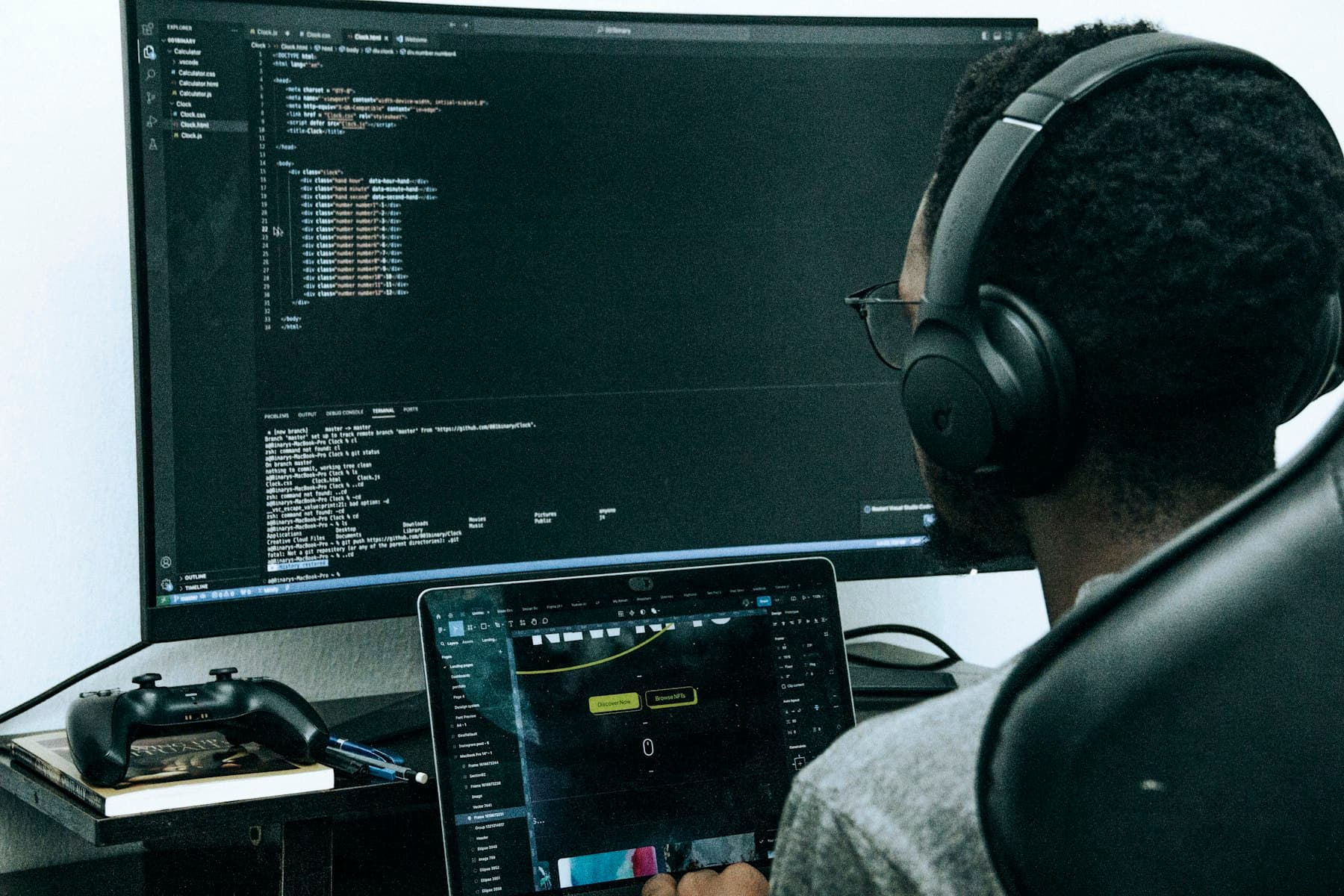 An engineer with headphones reviewing code on a large monitor