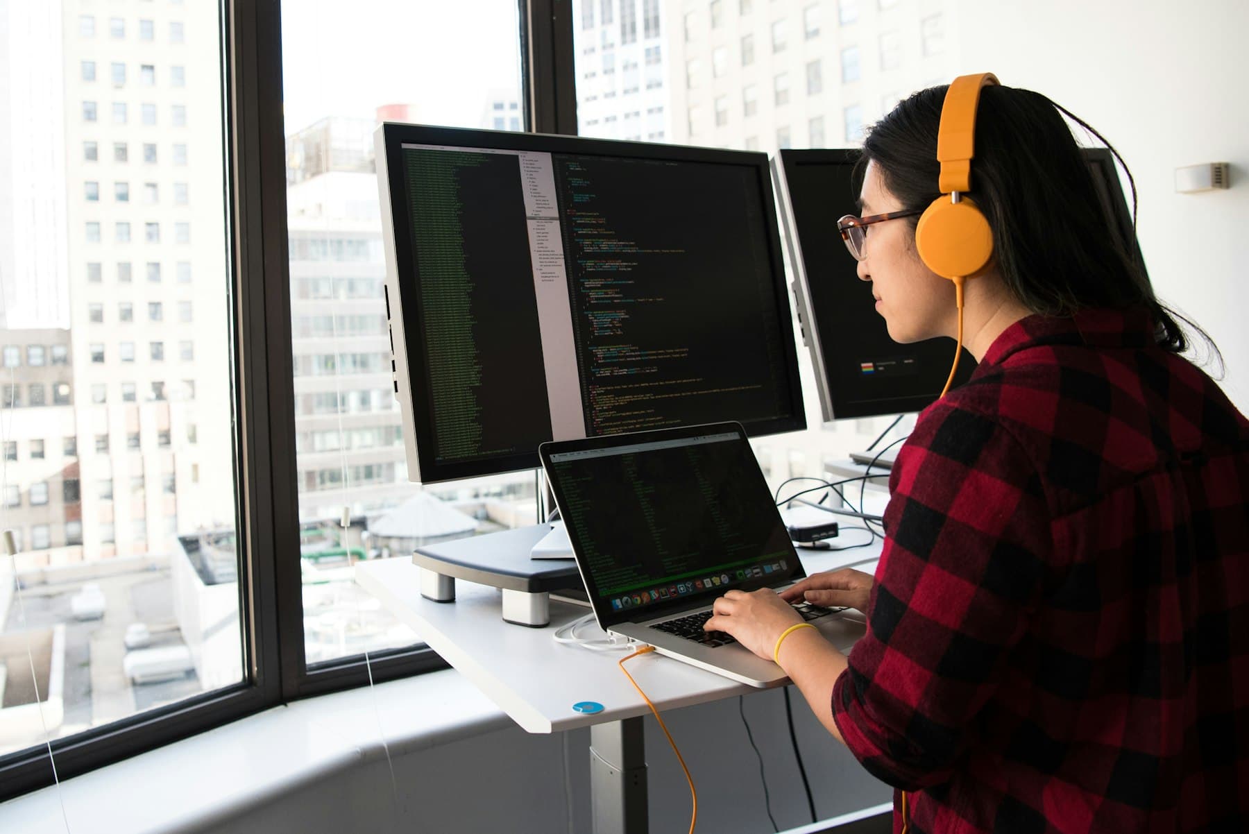 An engineer with headphones coding at a standing desk