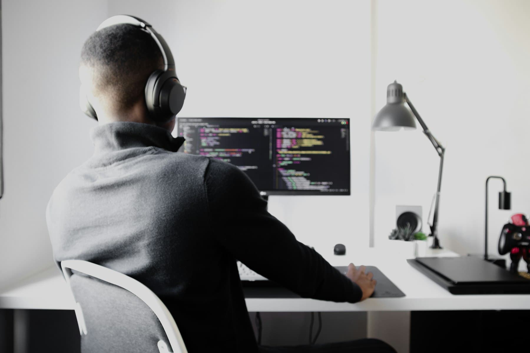 An engineer with headphones writing code at a clean desk