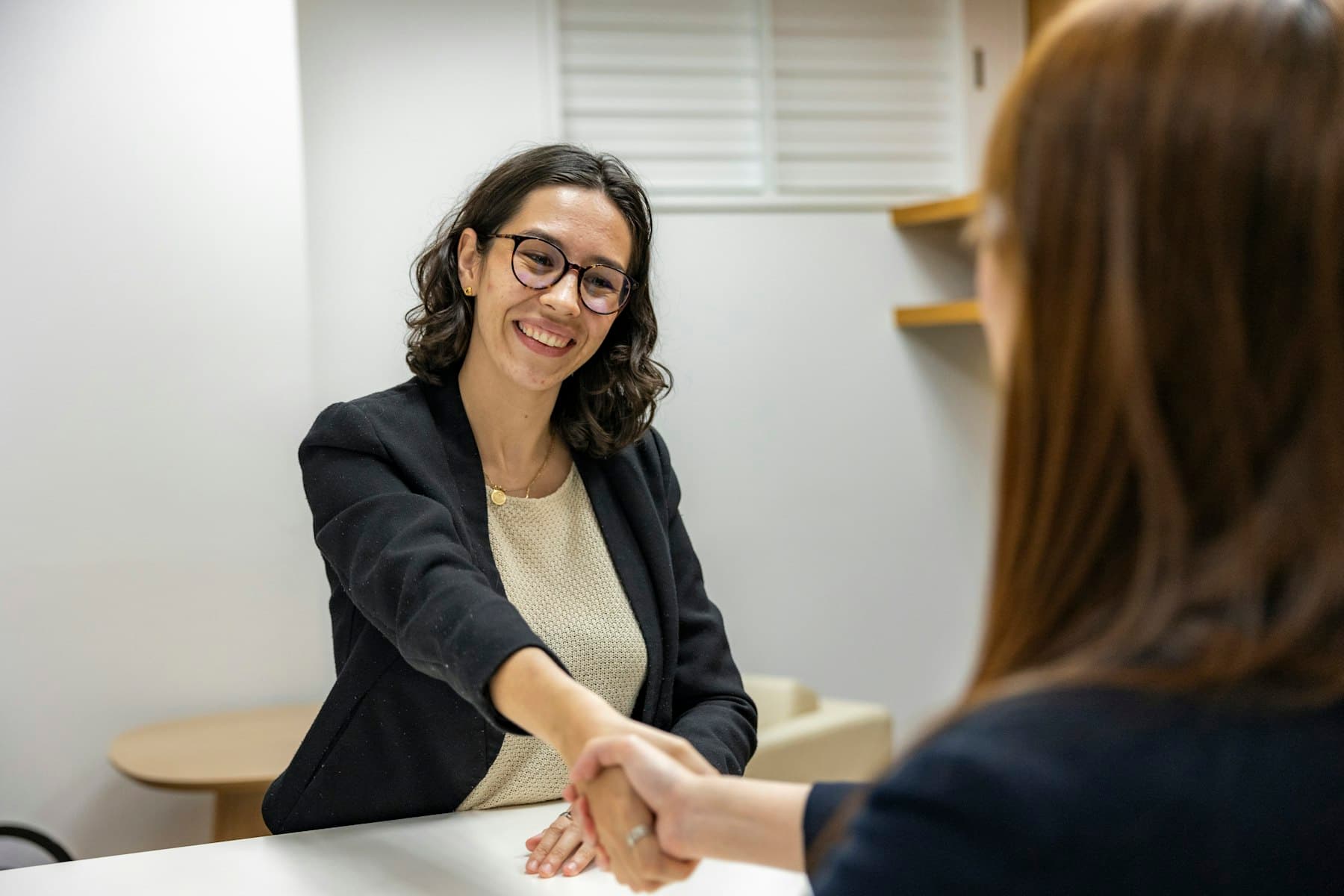 Two people shaking hands across a desk after an interview