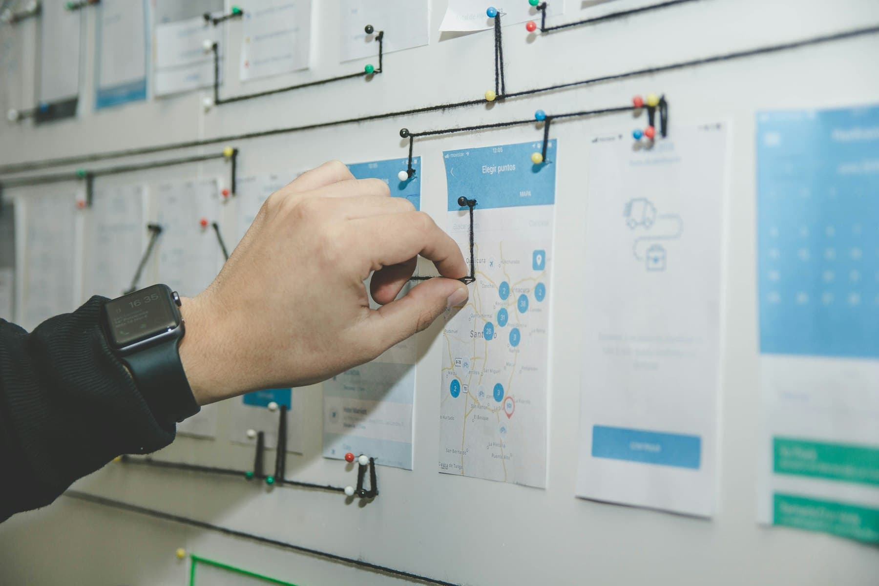 A designer arranging product wireframes on a wall