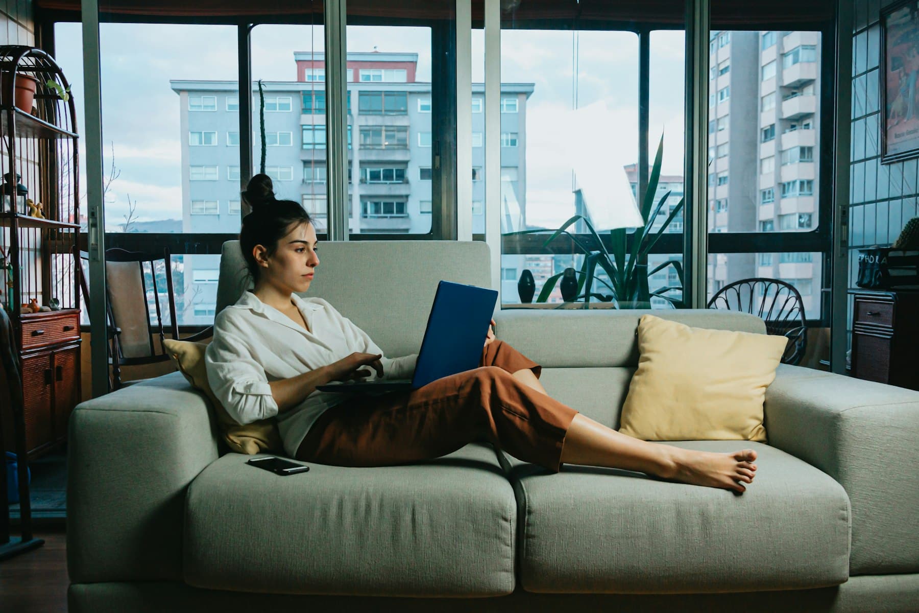 A woman working on a laptop from her sofa at home