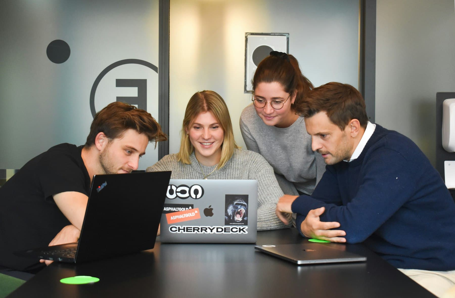 Four teammates looking at a laptop together