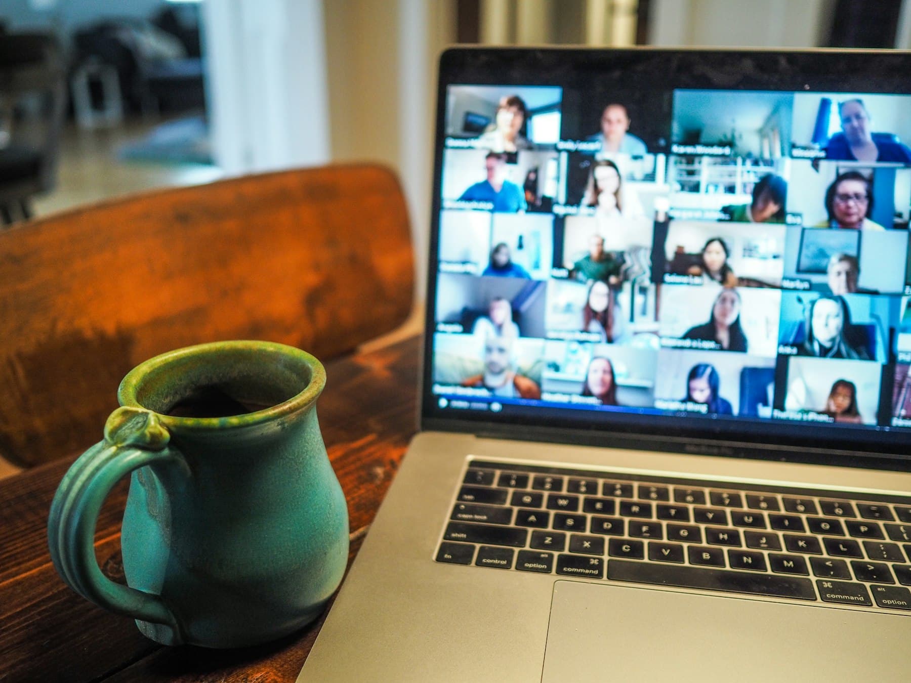 A laptop showing a team video call next to a coffee mug